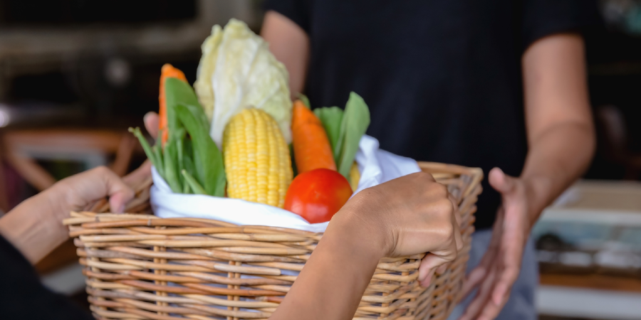 Person handing a food hamper to an elderly person